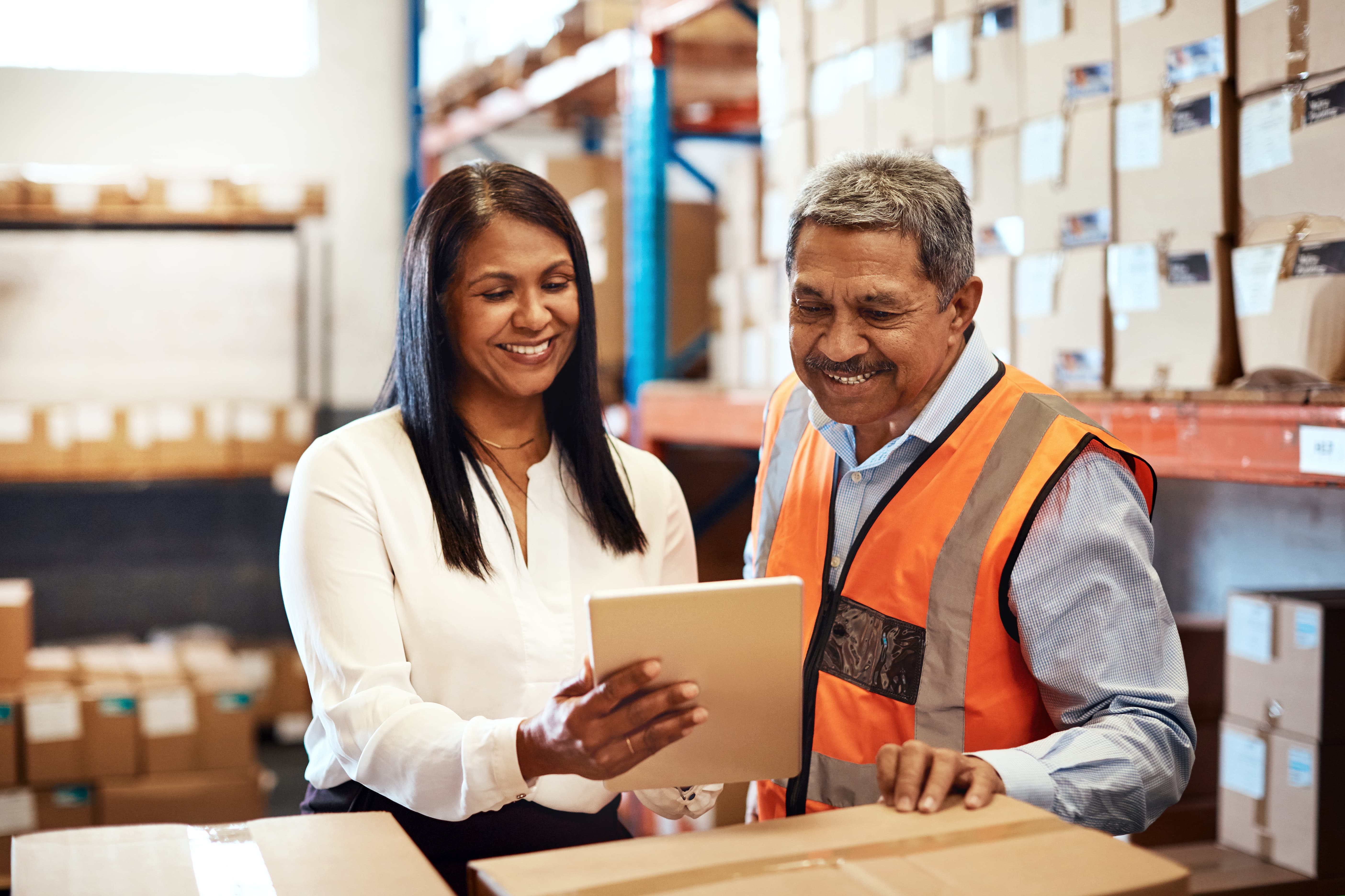 Man and woman in a warehouse looking at a tablet