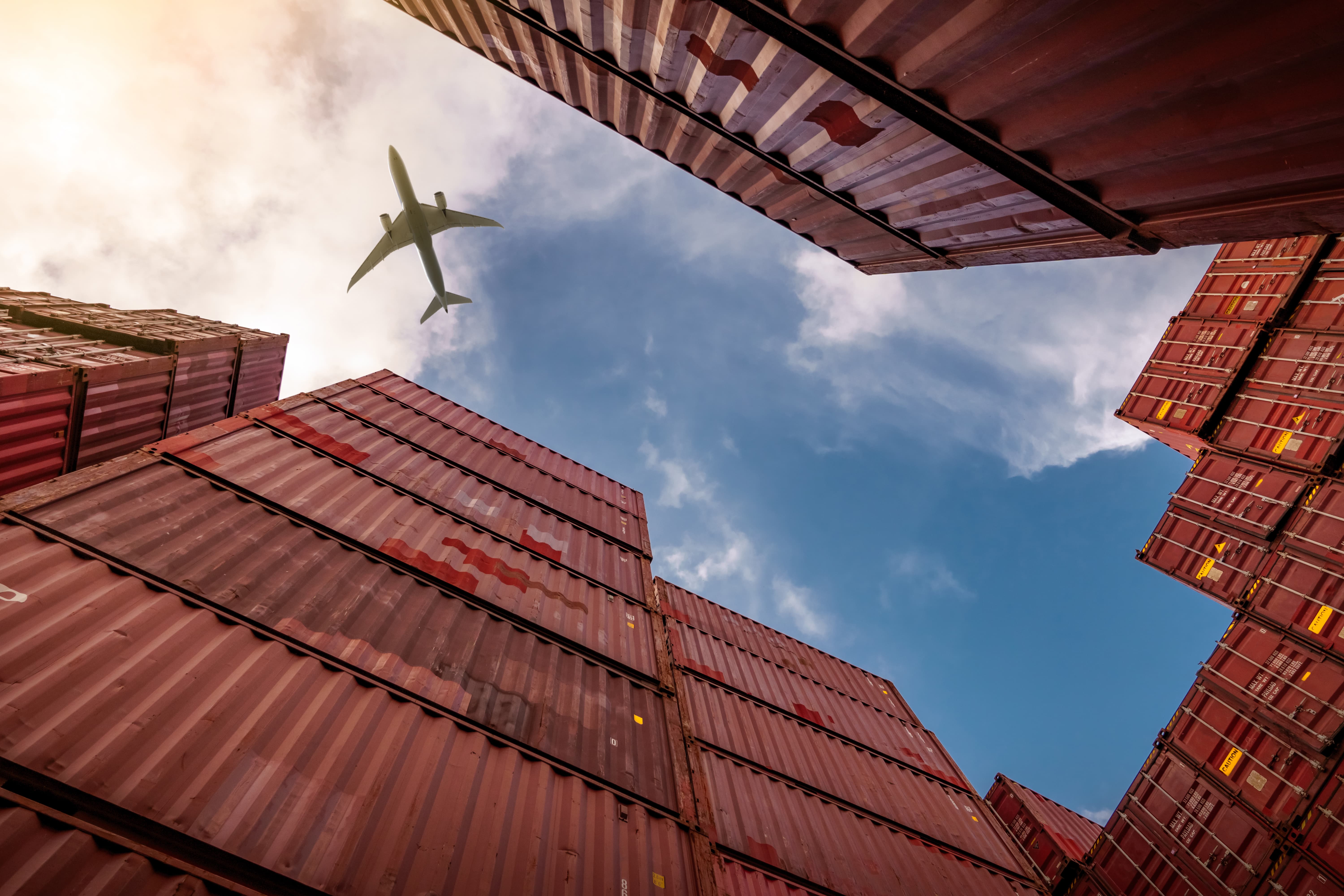 View of an airplane flying over shipping containers