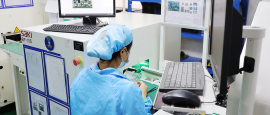 A woman works on a circuit board in a manufacturing centre