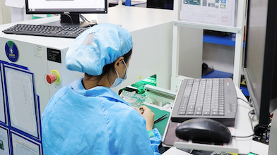 A woman works on a circuit board in a manufacturing centre