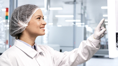 A woman in a clean suit working in a medical device manufacturing facility 